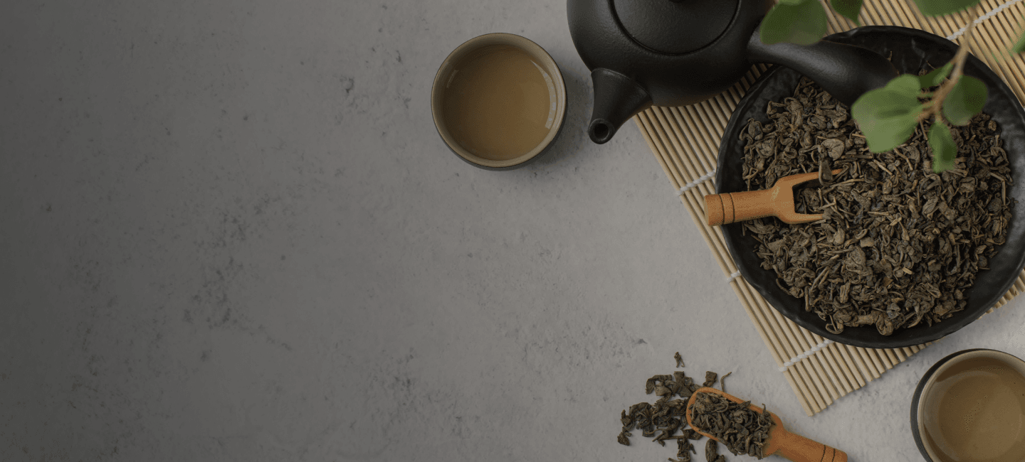 Loose-leaf green tea with a black teapot and cups